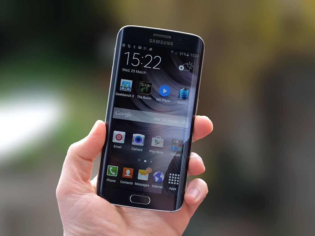 Samsung Galaxy S6 edge in hand displaying the home screen