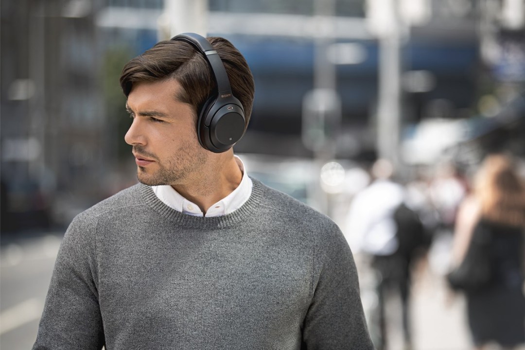 A man walking through the city wearing Sony wireless headphones