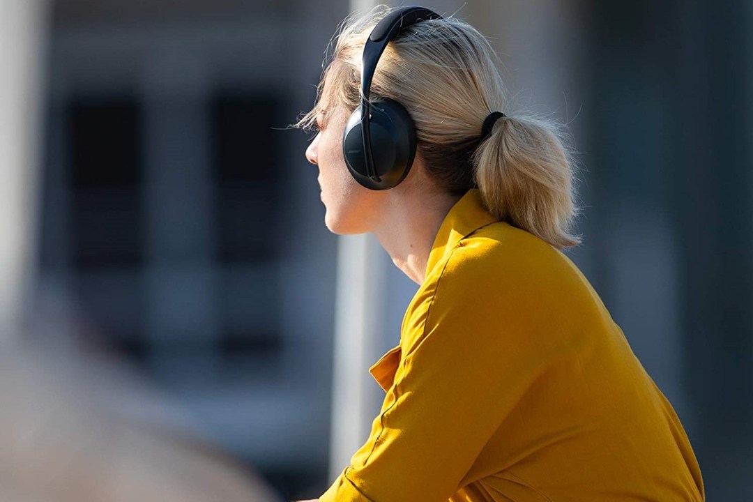 A woman in a yellow top listens to music on Bose headphones