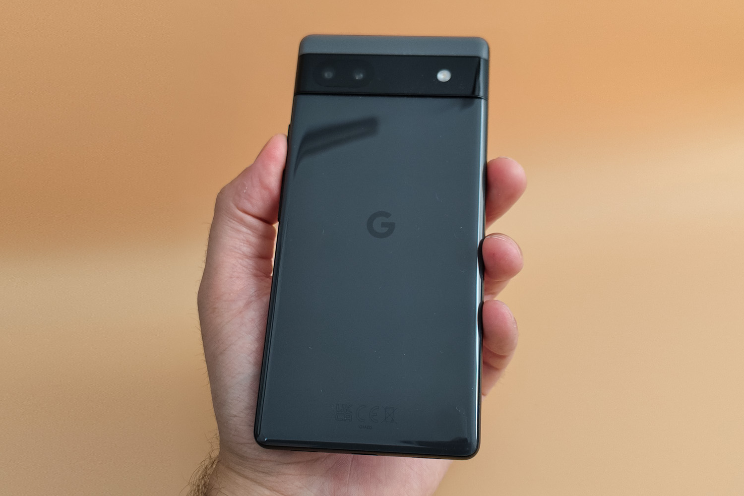 A hand holding the Google Pixel 6a, showing the rear side