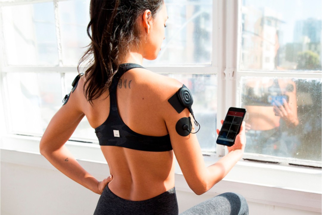 Woman using Therabody's PowerDot electrical muscle stimulation