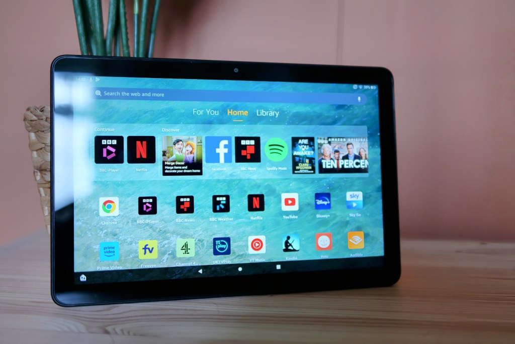 Amazon Fire HD 10 tablet leaning on a plant pot, showing screen