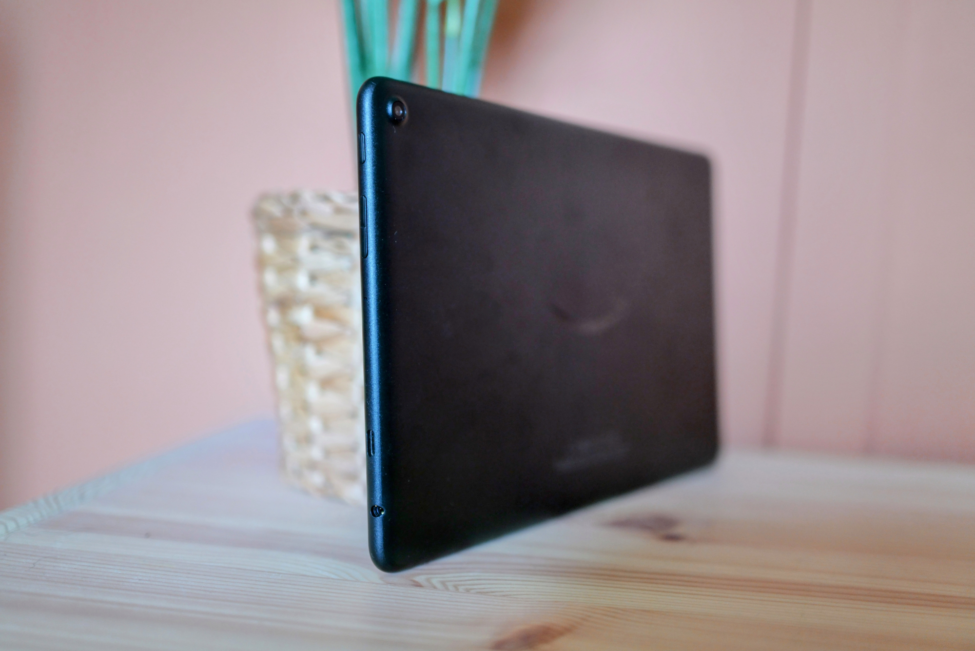Amazon Fire HD 10 tablet leaning on a plant pot, showing buttons