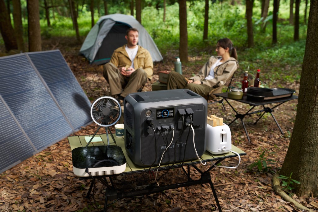 A couple camp in the woods with a poerable power bank and solar panels