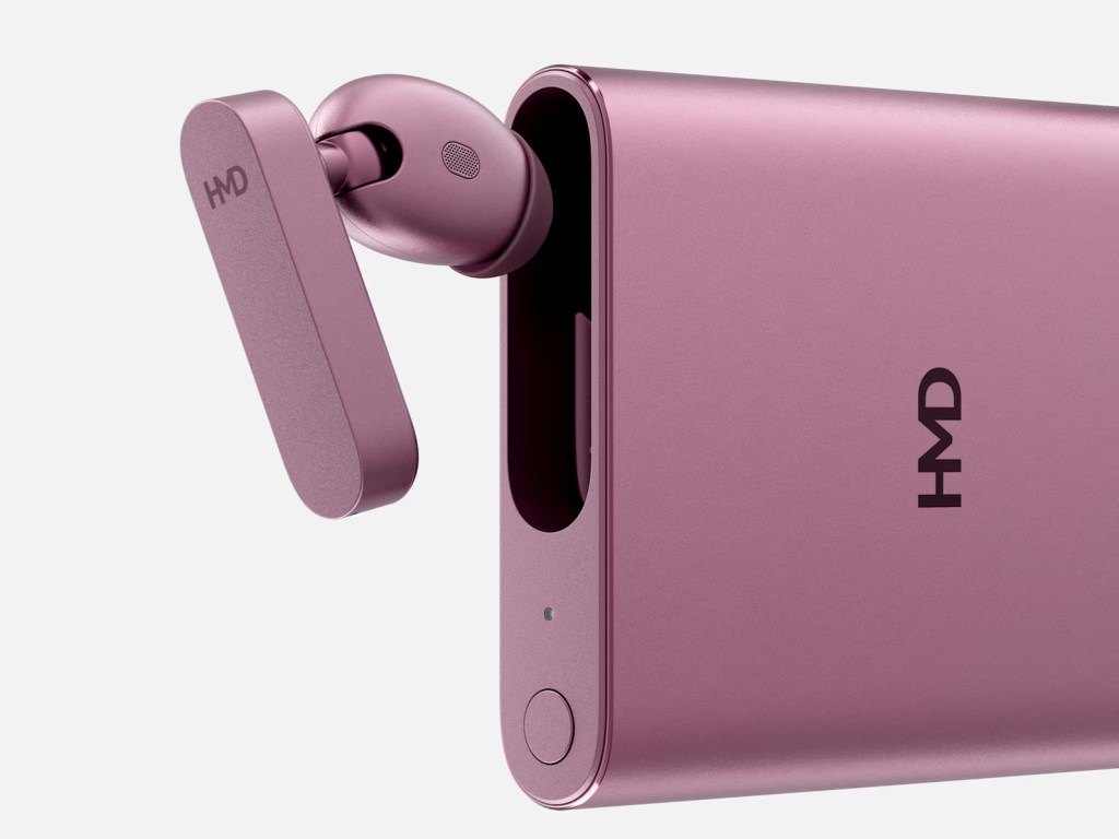 A close-up shot of the HDM Amped Buds slotting into the side of the charging case. Both are pink.