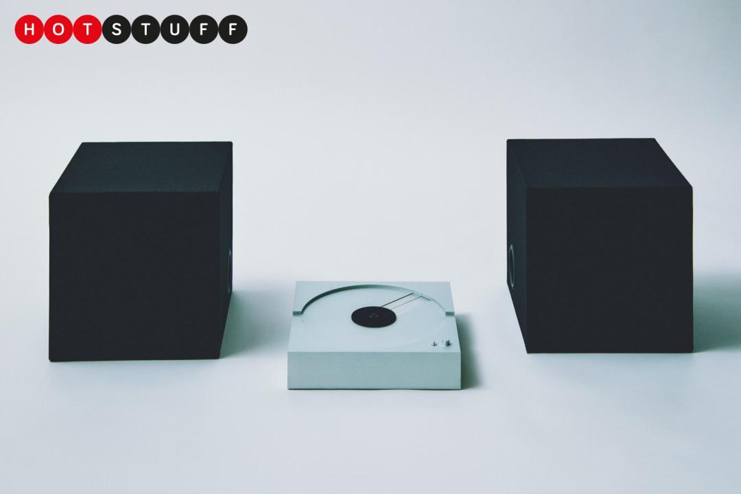 A silver turntable with a black cube-shaped speaker positioned on either side.