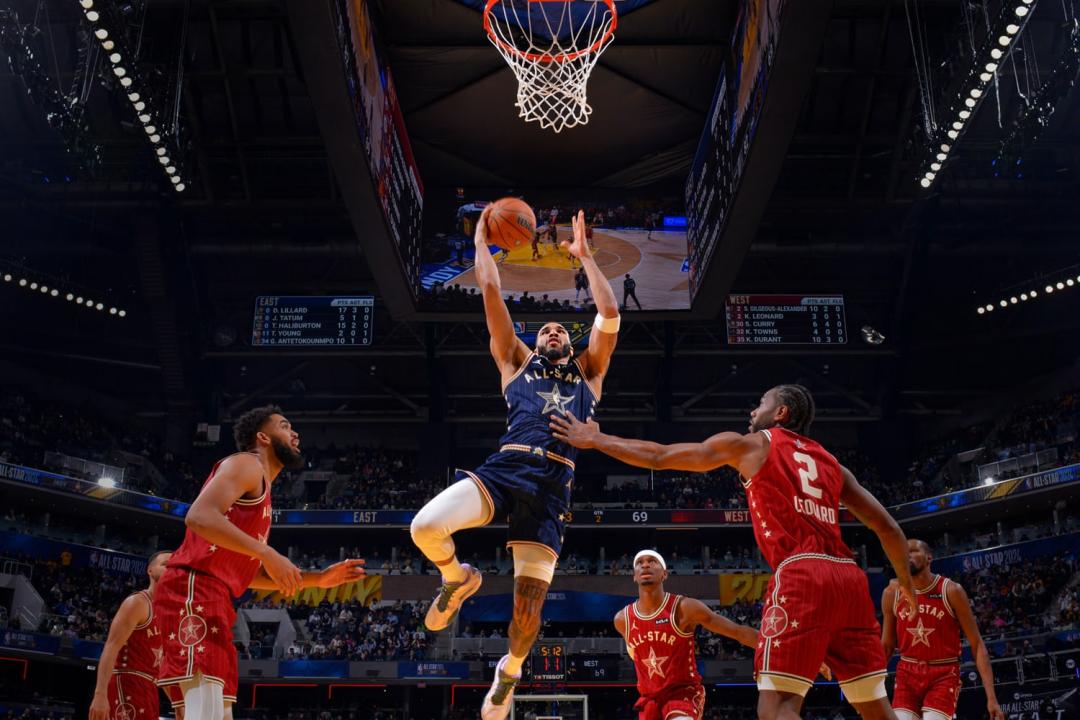 An nba player dunking a basketball between two defenders