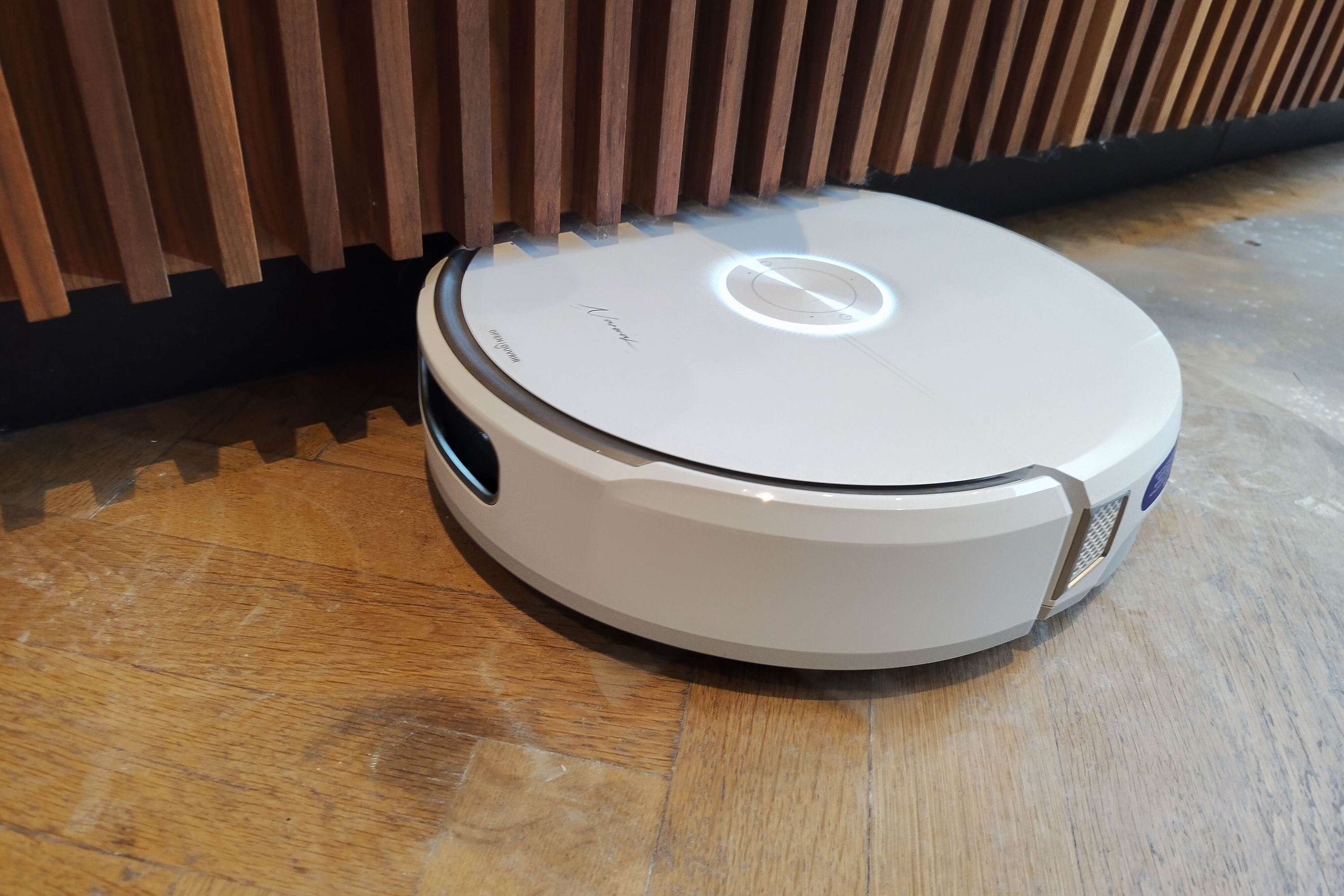 A robot vacuum cleaner under the edge of a kitchen cupboard