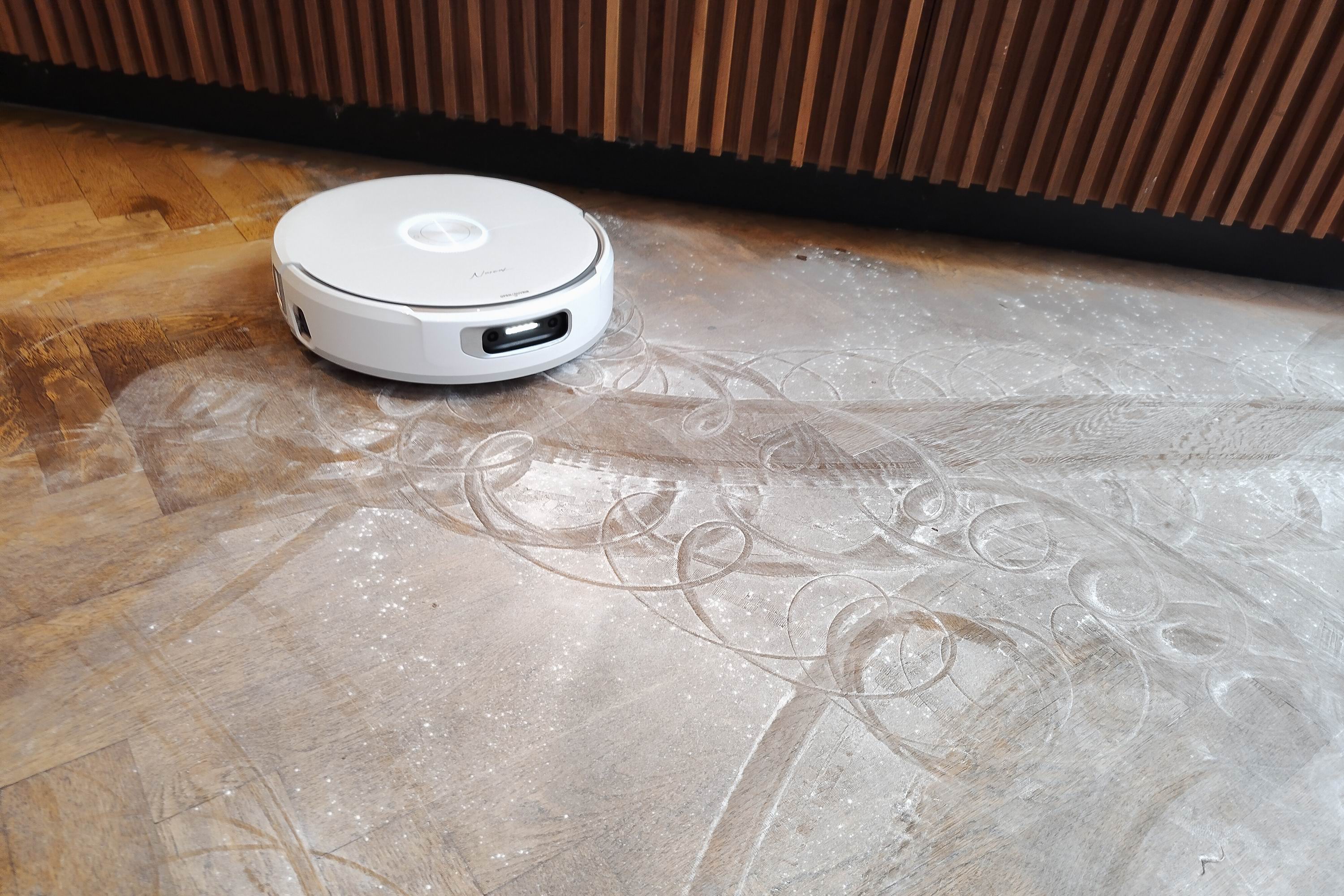 A robot vacuum cleaner on a wooden floor covered in baby powder