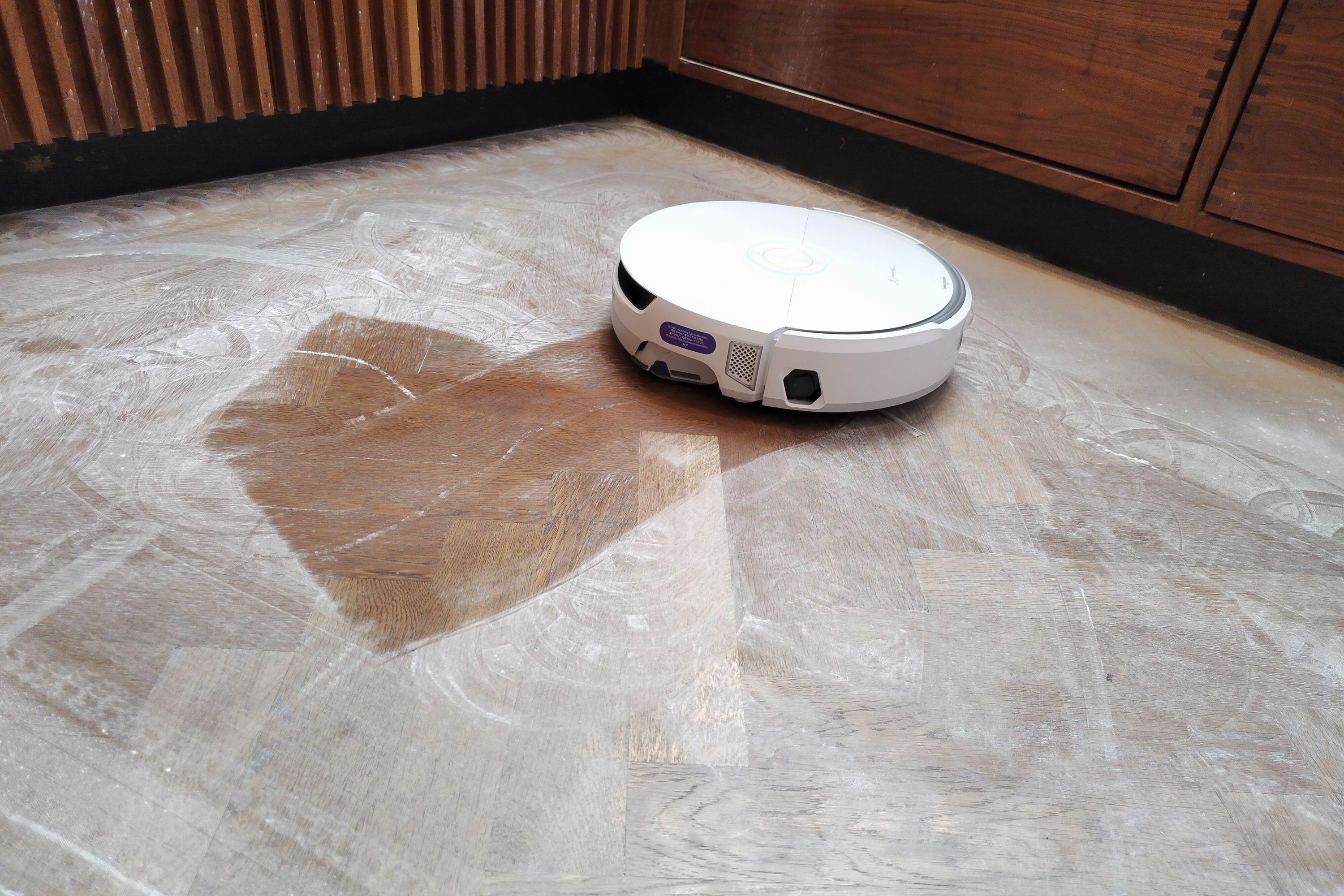 A robot vacuum mops baby powder from a wooden floor