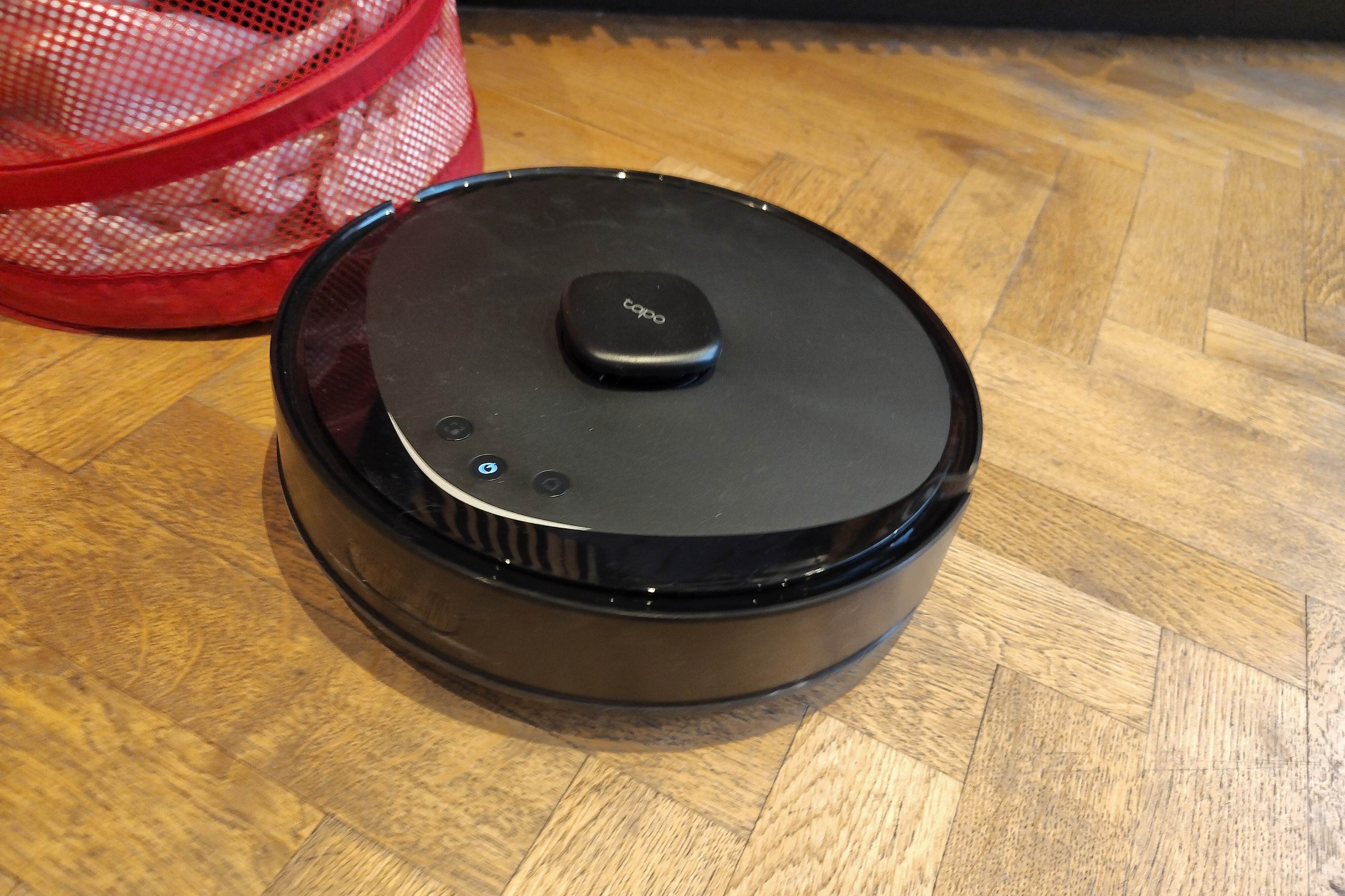 A robot vacuum cleaner next to a laundry basket
