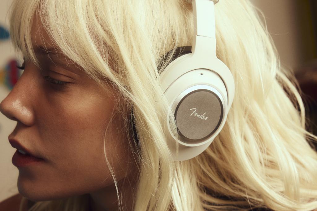 A close-up of a woman with blonde hair wearing a white pair of Fender Mix headphones
