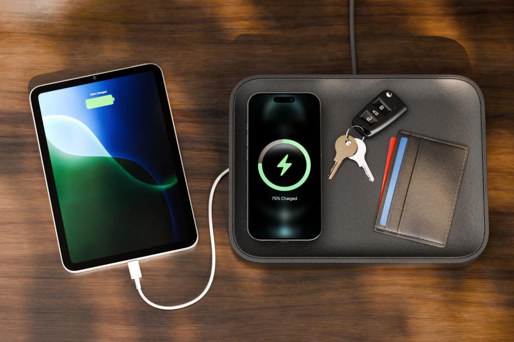 A top-down view of a Twelve South Valet charging tray. It contains a smartphone, keys and a wallet. To the left, a tablet is connected to the built-in USB port.