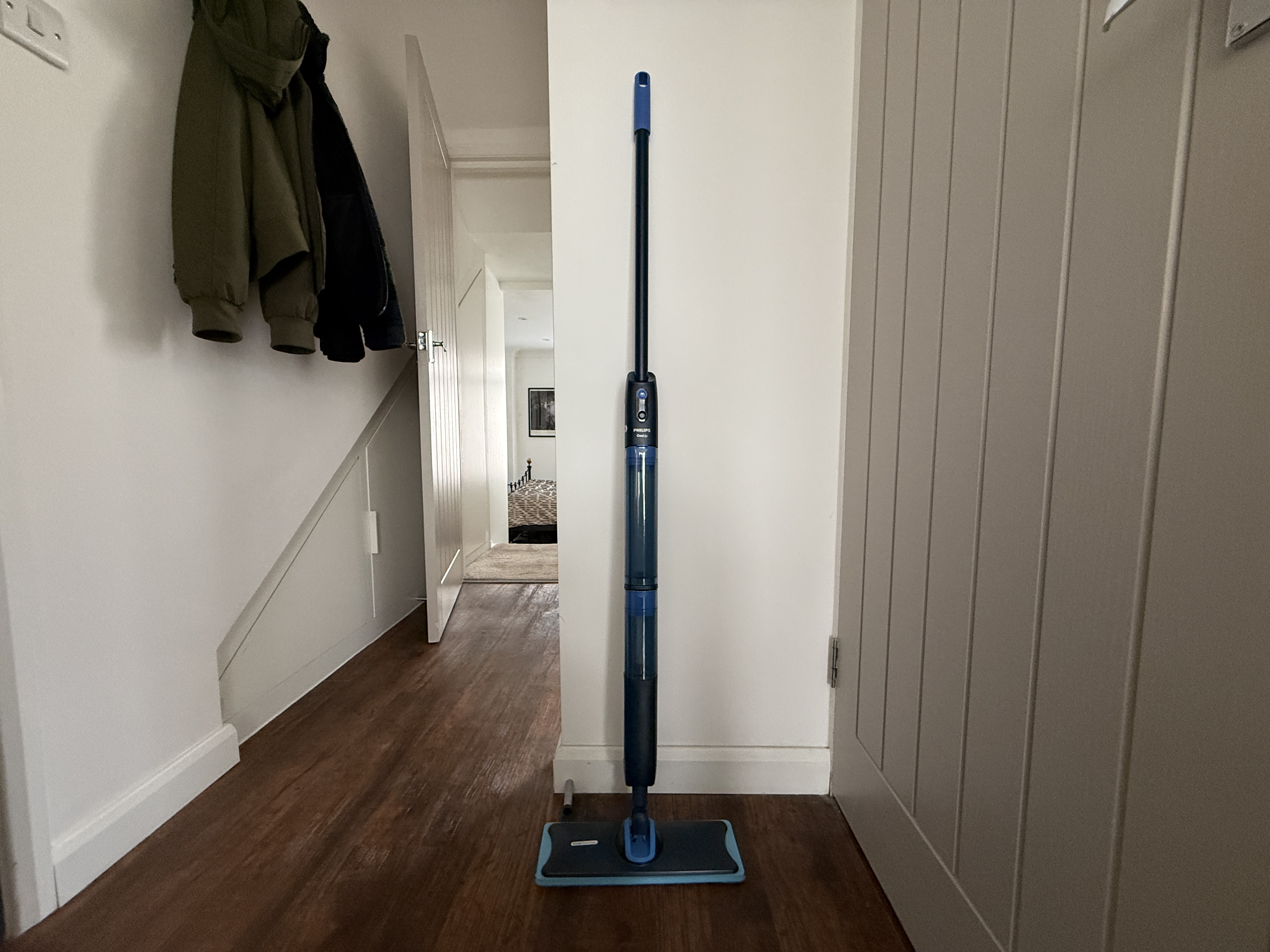 A Philips OneUp 5000 electric mop propped up against a wall in a hallway