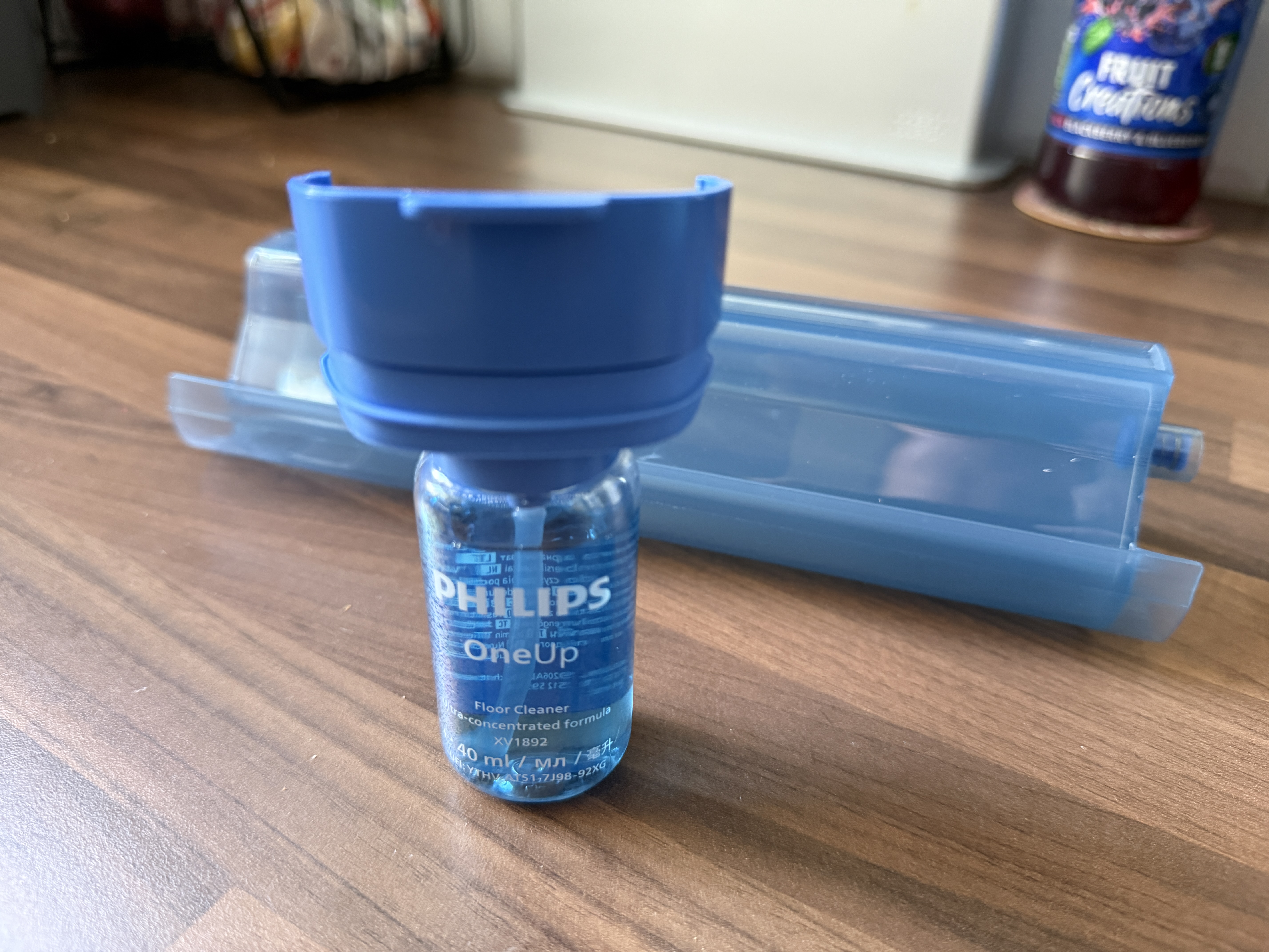 A bottle of cleaning fluid screwed into the lid of the water tank for a Philips OneUp 5000 electric mop